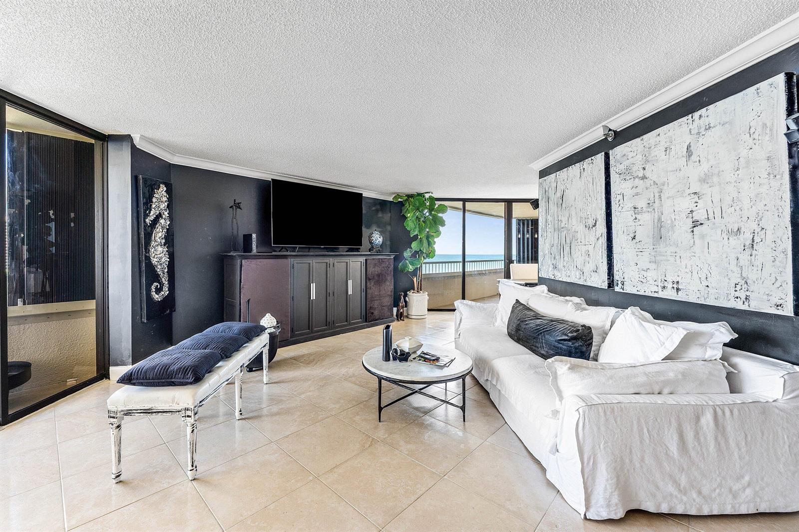 A living room with black walls, a white sofa, and a balcony overlooking the ocean — 5080 N Ocean Drive # 6b, Singer Island FL 33404, SINGER ISLAND, FL