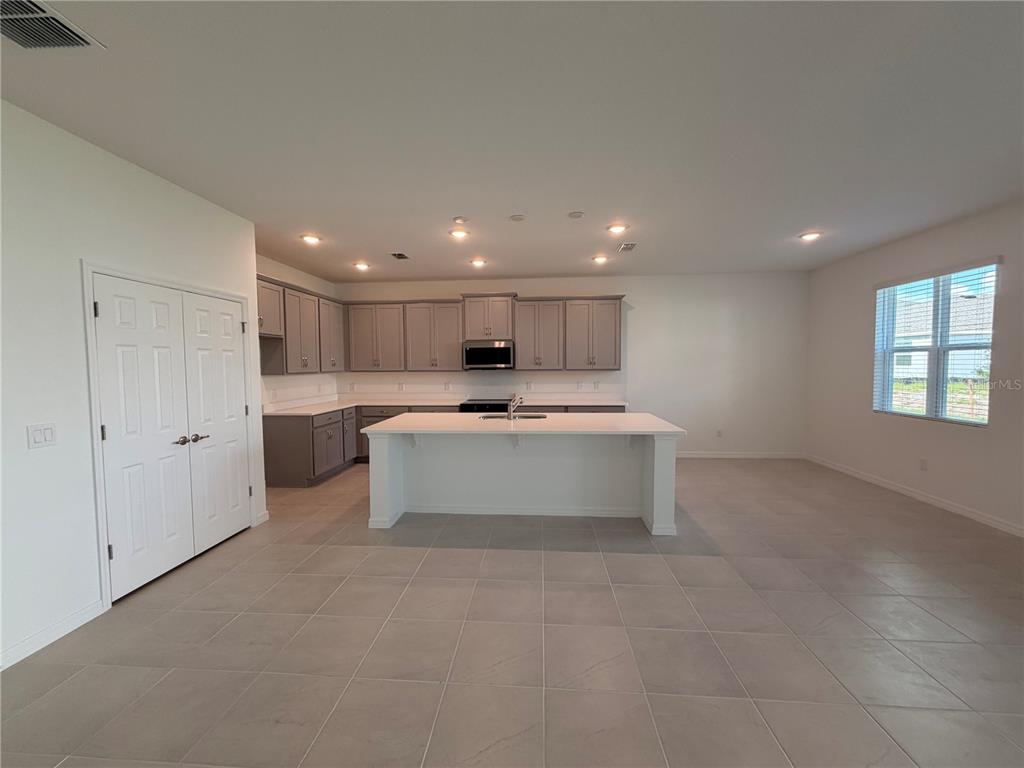 A kitchen with gray cabinets, a white island, and tile flooring in an open space — 2011 EDUCATION STREET, ST CLOUD, FL