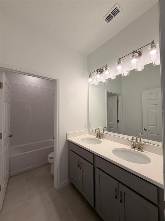 A bathroom features a double vanity with grey cabinets, a large mirror, and a tub-shower — 2011 EDUCATION STREET, ST CLOUD, FL