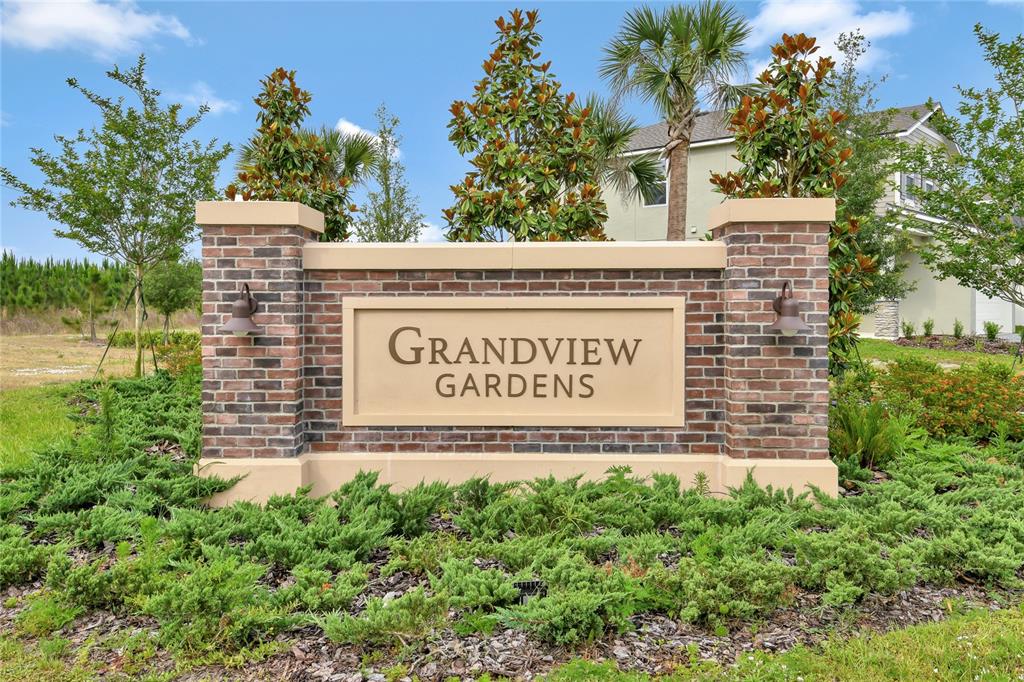 A brick monument sign for Grandview Gardens stands in a landscaped yard with trees — 1774 CARNELIAN STREET, DELAND, FL