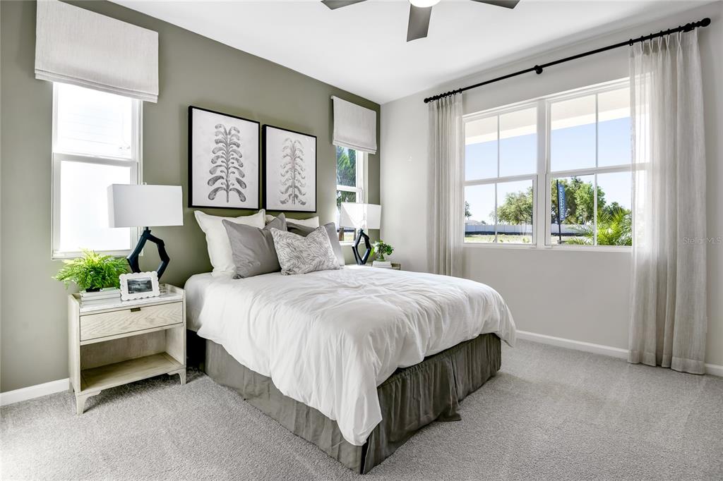A bedroom features a bed with white bedding, two nightstands, and windows with sheer curtains — 1774 CARNELIAN STREET, DELAND, FL