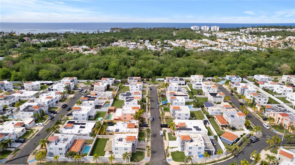 An aerial view shows a residential neighborhood with white houses, green trees, and the ocean — Estancias De Cerro Grodo CALLE PLAZA FABIAN UNIT 63, VEGA ALTA, PR