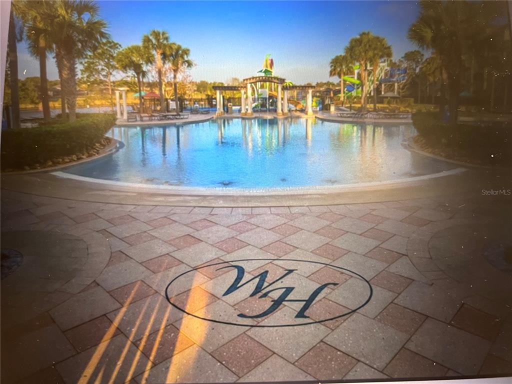 A swimming pool with a water slide and a pergola sits behind a paved patio — 2781 ALMATON LOOP UNIT 304, KISSIMMEE, FL