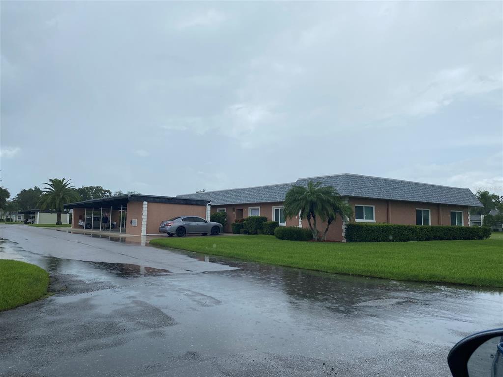 A single-story building with a covered carport and a lawn under a cloudy sky — 9609 MIDIRON COURT UNIT 1, NEW PORT RICHEY, FL