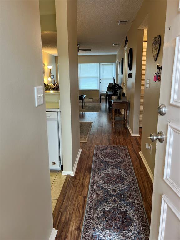 An entryway leads into a hallway with wood-look flooring, a runner rug, and a kitchen area — 9609 MIDIRON COURT UNIT 1, NEW PORT RICHEY, FL