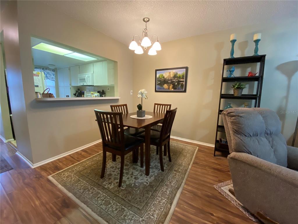 A dining area features a wooden table with four chairs, a rug, and a chandelier — 9609 MIDIRON COURT UNIT 1, NEW PORT RICHEY, FL