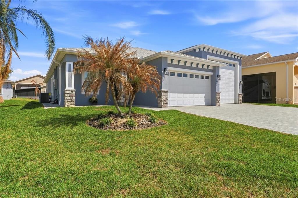 A single-story house with a gray exterior, stone accents, and a two-car garage — 517 HOME COMING WAY, POLK CITY, FL