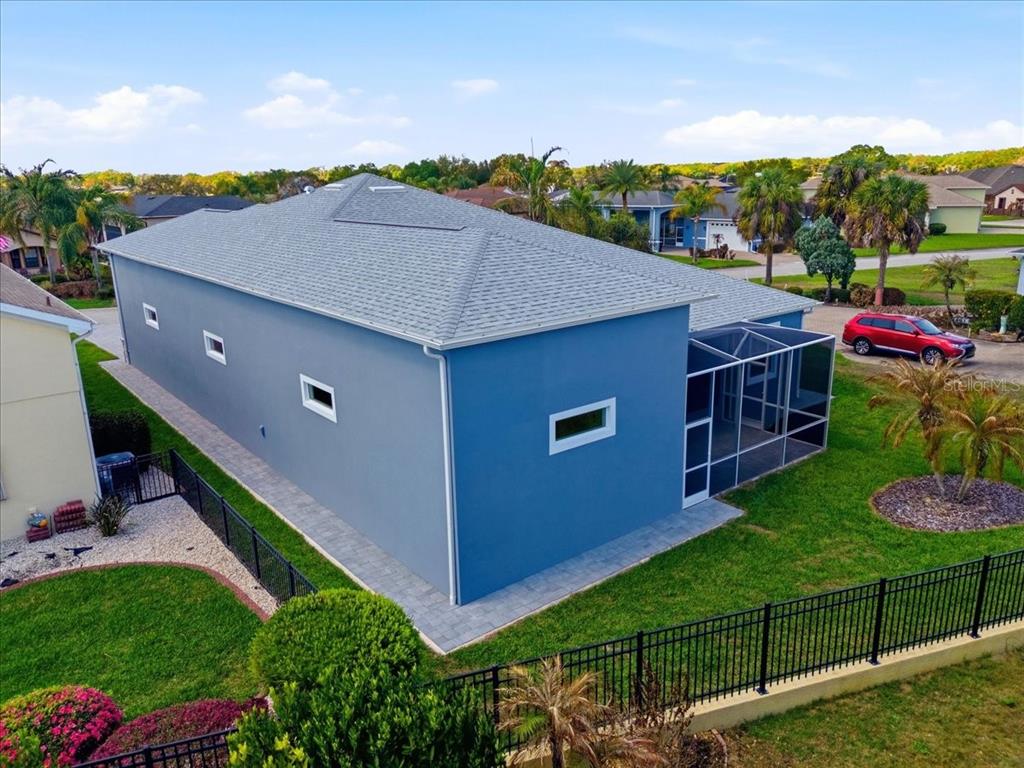 An aerial view of a blue house with a gray shingled roof and screened lanai — 517 HOME COMING WAY, POLK CITY, FL
