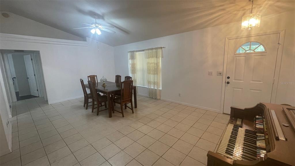 A dining area with tile floors, a wooden table, and an upright piano near the entrance — 32 ALMOND DRIVE, OCALA, FL