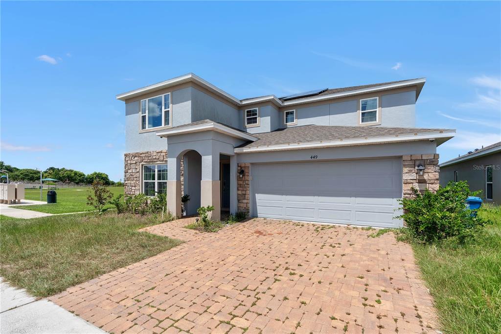 A two-story house with a stone-accented facade, a two-car garage, and a paved driveway — 449 TORTUGAS STREET, HAINES CITY, FL