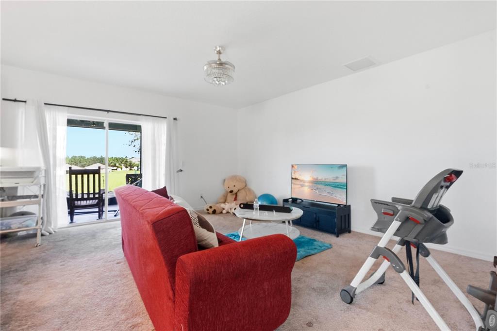 A living room features a red sofa, a television on a stand, and a high chair — 449 TORTUGAS STREET, HAINES CITY, FL
