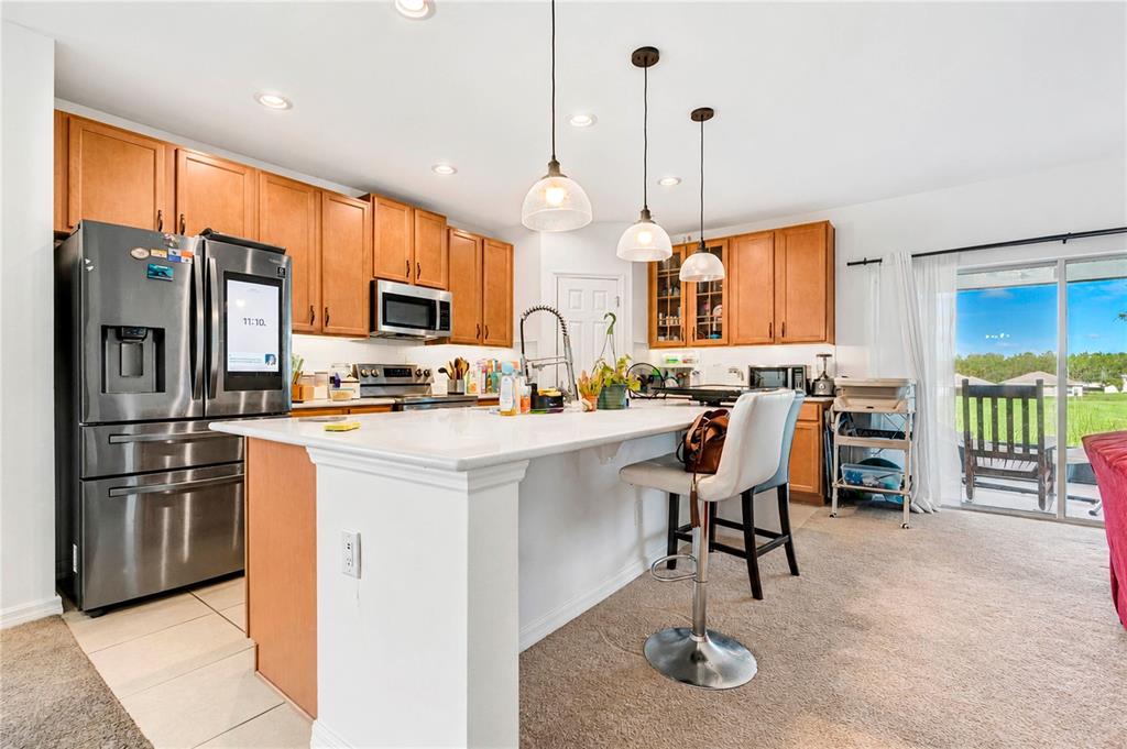 A kitchen features wood cabinets, stainless steel appliances, a white island, and a sliding glass door — 449 TORTUGAS STREET, HAINES CITY, FL