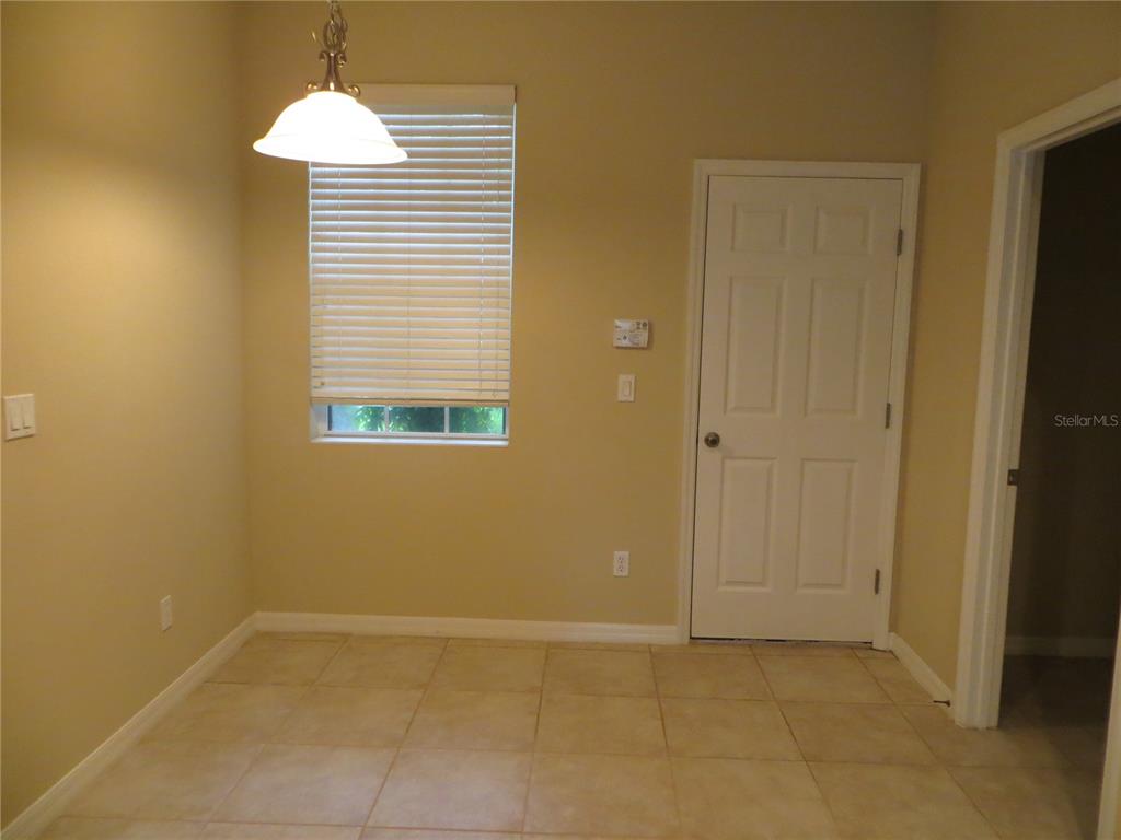A room with tan walls, tile flooring, a window with blinds, and a white door — 5303 CAPE HATTERAS DRIVE, CLERMONT, FL