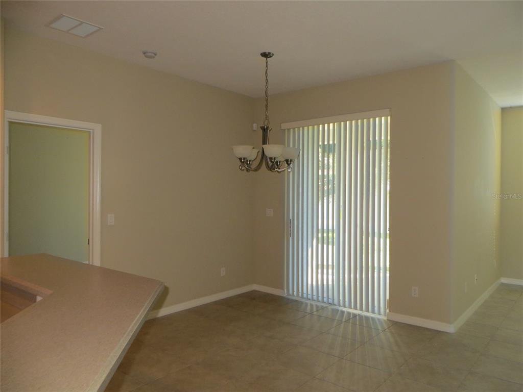 A dining area with tile flooring, a chandelier, and sliding glass doors leading outside — 5303 CAPE HATTERAS DRIVE, CLERMONT, FL