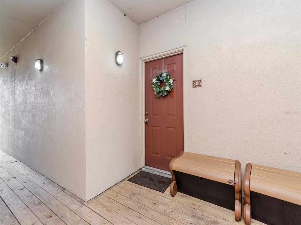 A brown door with a wreath and unit number 306 sits on a wooden deck — 1429 VILLA CAPRI CIRCLE UNIT 306, ODESSA, FL