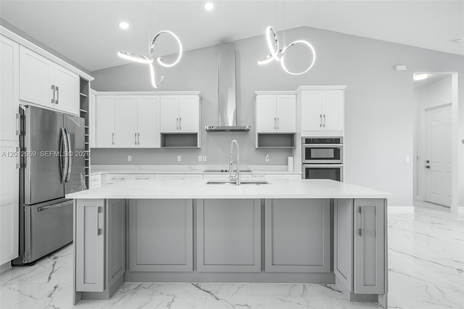 A modern kitchen features a gray island, white cabinetry, stainless steel appliances, and marble flooring — 1025 Greenway Ter # 1025, Sebring FL 33876, SEBRING, FL