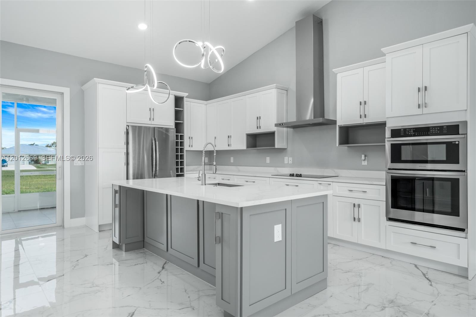 A modern kitchen features white cabinetry, a gray island, stainless steel appliances, and marble flooring — 1025 Greenway Ter # 1025, Sebring FL 33876, SEBRING, FL