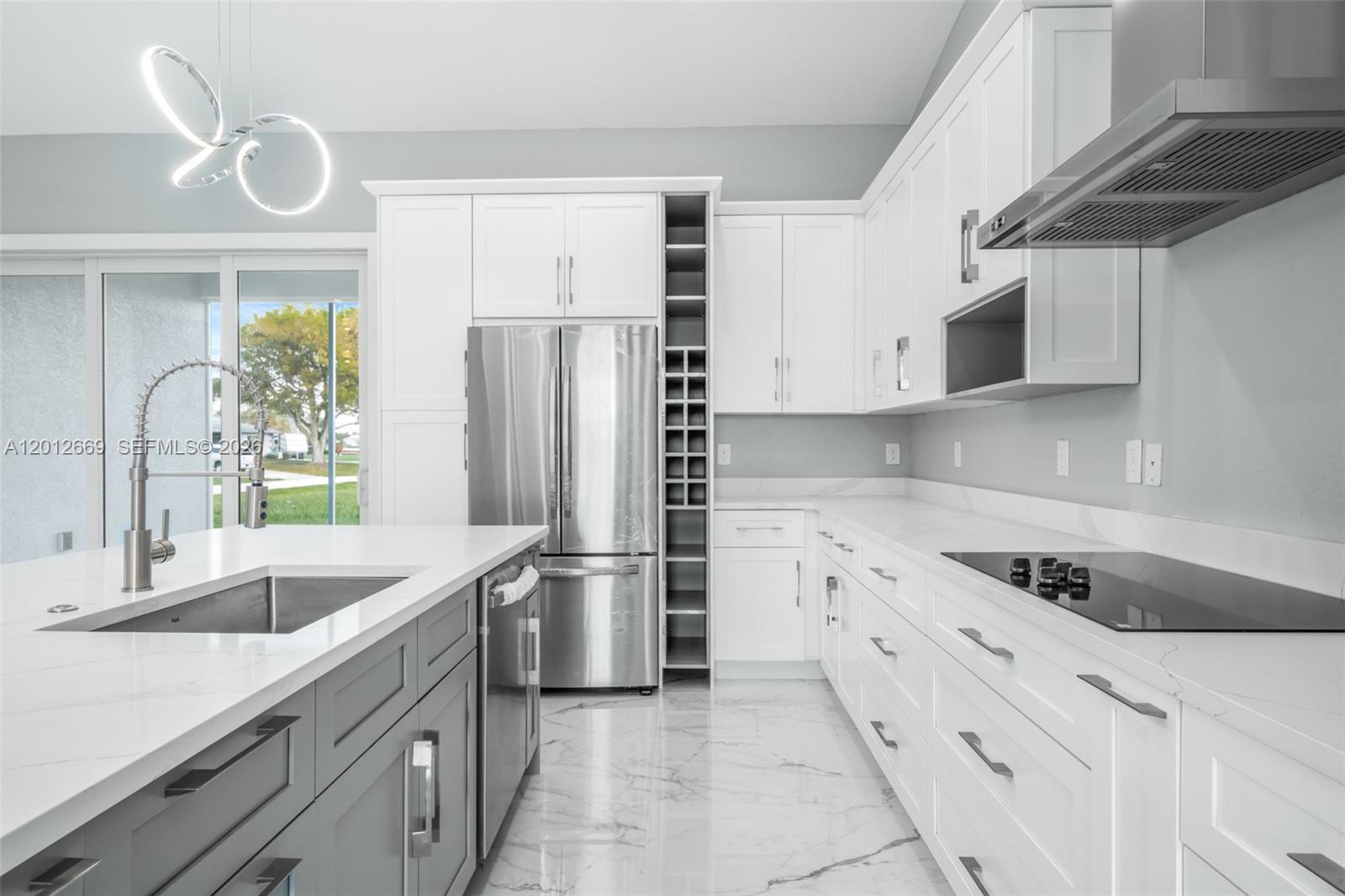A modern kitchen features white cabinets, a gray island, stainless steel appliances, and marble flooring — 1025 Greenway Ter # 1025, Sebring FL 33876, SEBRING, FL