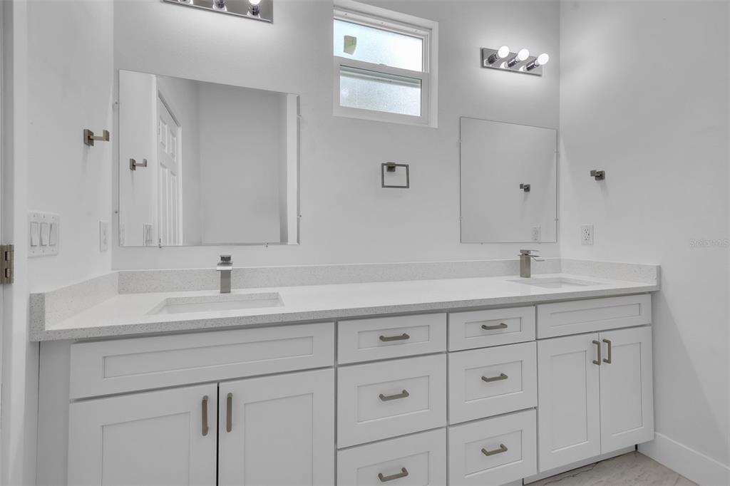 A modern bathroom features a white double vanity with quartz countertops and two square mirrors — 1221 SW 5TH STREET, OCALA, FL
