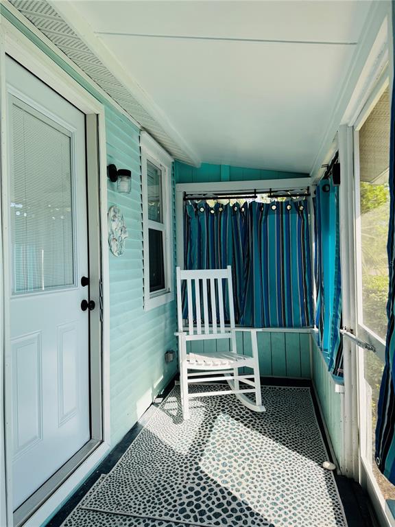 A covered porch with light blue siding, a white rocking chair, and a patterned rug — 6980 POINSETTA, LONGBOAT KEY, FL