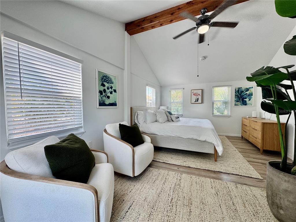 A bedroom features a vaulted ceiling with exposed beams, white walls, and two armchairs — 6980 POINSETTA, LONGBOAT KEY, FL