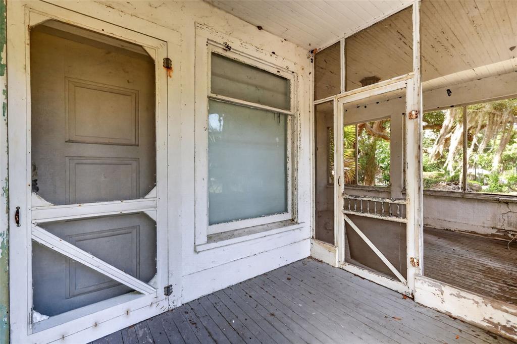 A weathered, white-painted screened porch features wooden flooring, a screen door, and large windows — 316 N HIGHLAND STREET, MOUNT DORA, FL
