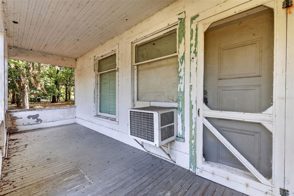 A weathered porch features a wooden floor, a screen door, and a window air conditioning unit — 316 N HIGHLAND STREET, MOUNT DORA, FL