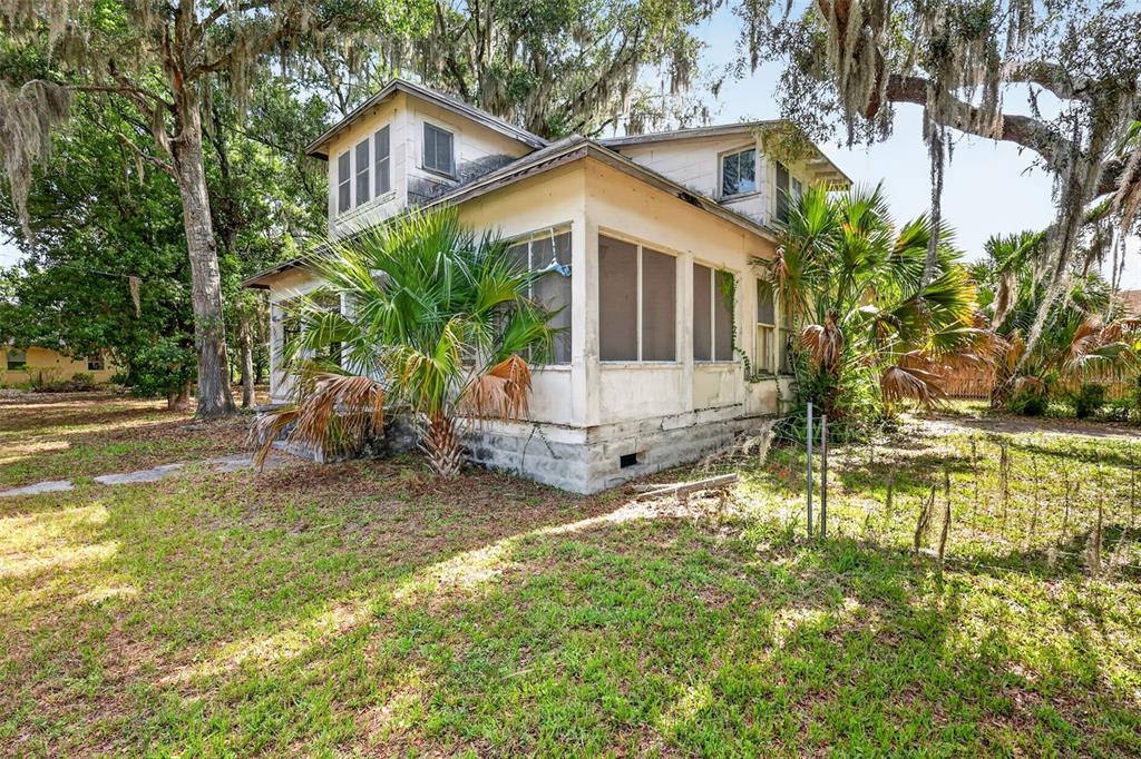 A two-story house with a screened-in porch, weathered siding, and palm trees in the yard — 316 N HIGHLAND STREET, MOUNT DORA, FL