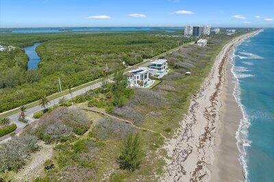 An aerial view shows a coastal property with two houses situated between a road and the ocean — FORT PIERCE, FL