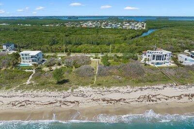 An aerial view shows two beachfront houses separated by a vacant lot near a forest — FORT PIERCE, FL