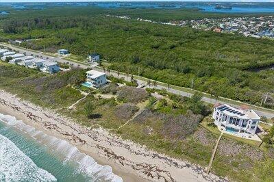 An aerial view shows beachfront houses along a coastal road next to dense green vegetation — FORT PIERCE, FL