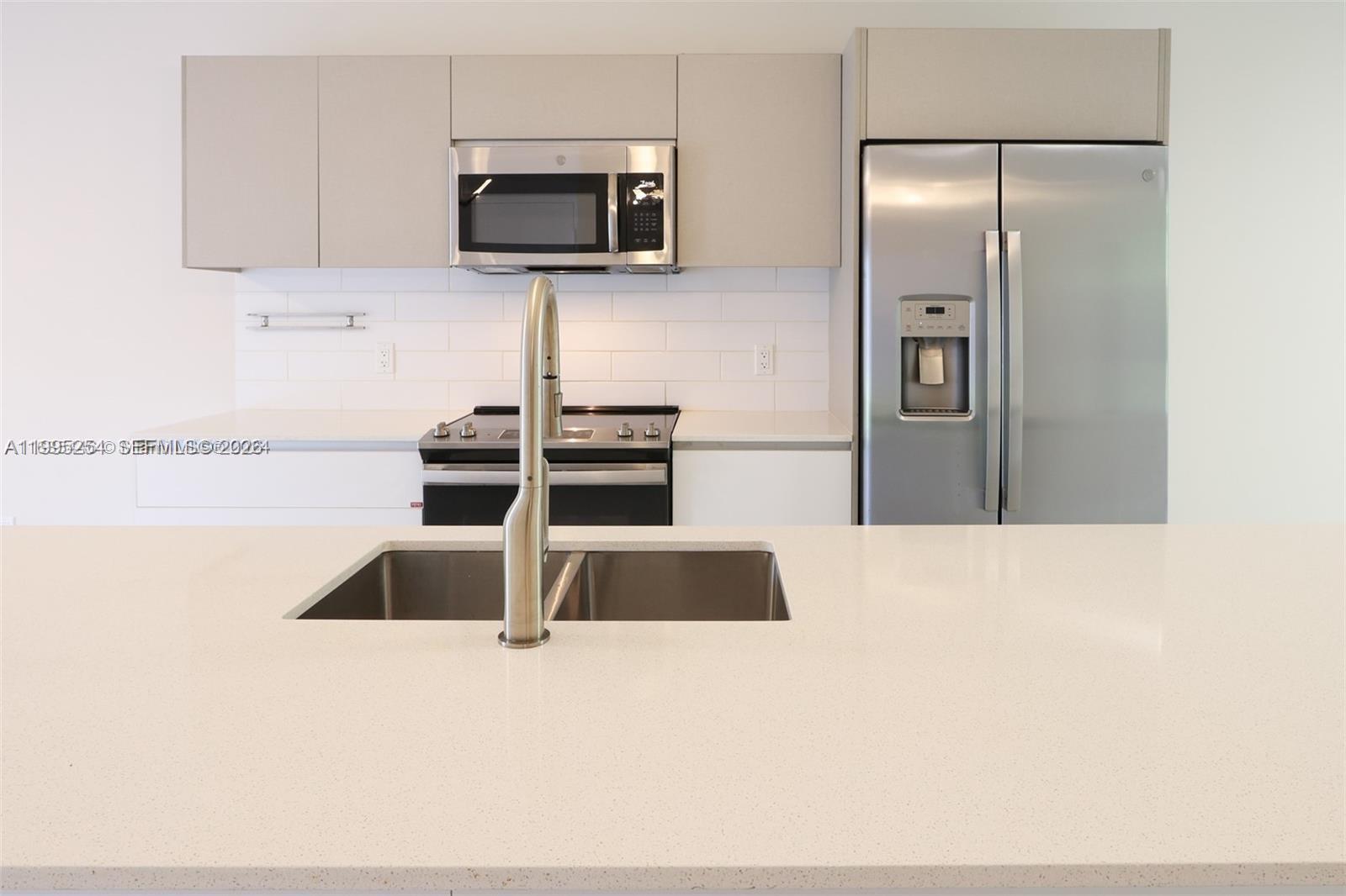 A modern kitchen features white countertops, stainless steel appliances, and light-colored cabinetry — 2555 NE 193rd St # 2206, Miami FL 33180, MIAMI, FL