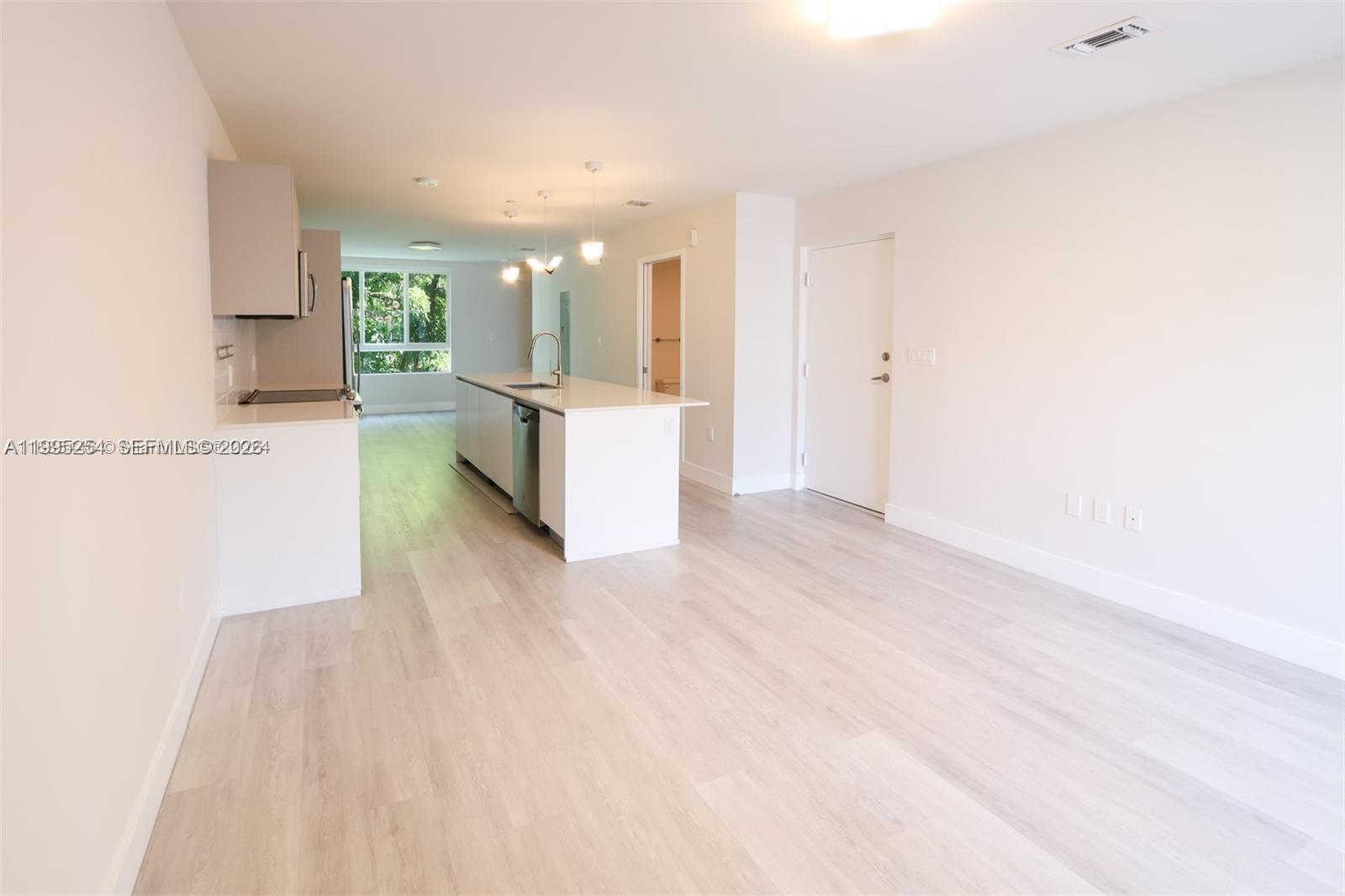 A modern kitchen with white cabinets and an island opens into a living area — 2555 NE 193rd St # 2206, Miami FL 33180, MIAMI, FL