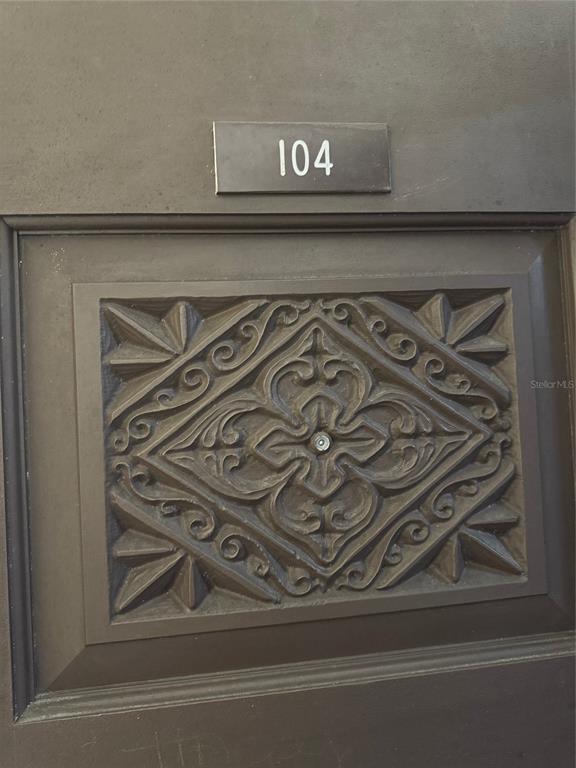 A dark brown door features an ornate, carved diamond-shaped panel and the number 104 — 2225 HOLDEN AVENUE UNIT 104, ORLANDO, FL