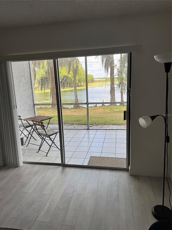 A room with light wood flooring looks through a sliding glass door to a screened patio — 2225 HOLDEN AVENUE UNIT 104, ORLANDO, FL