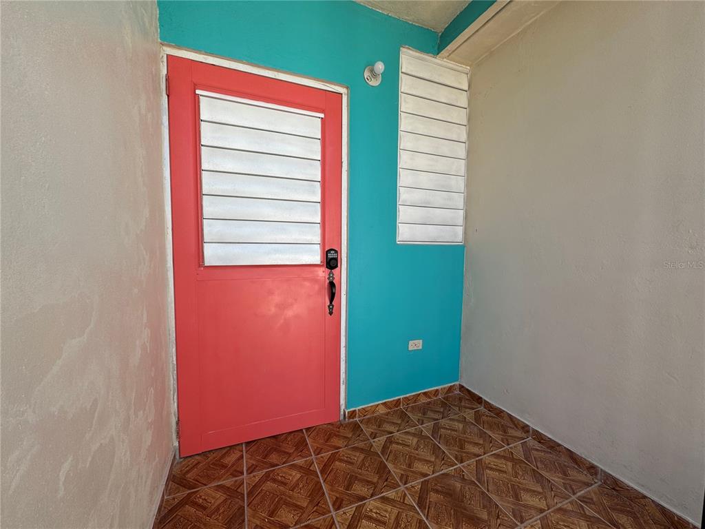 A narrow room features tiled flooring, two exterior doors, and louvered windows on two walls — PASEO MAGDALENA ST. URB. LEVITTOWN LAKES UNIT 11-AK, TOA BAJA, PR
