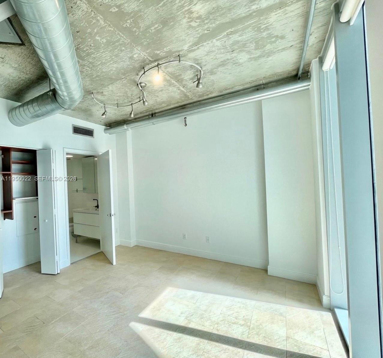 An interior room features a concrete ceiling, track lighting, tile flooring, and an attached bathroom — 690 SW 1st Ct # 2134, Miami FL 33130, MIAMI, FL