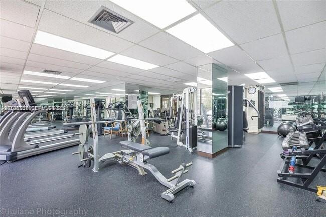 This gym features various exercise machines, mirrored walls, and a drop ceiling with recessed lighting — 1965 S Ocean Dr # 9K, Hallandale Beach FL 33009, HALLANDALE BEACH, FL