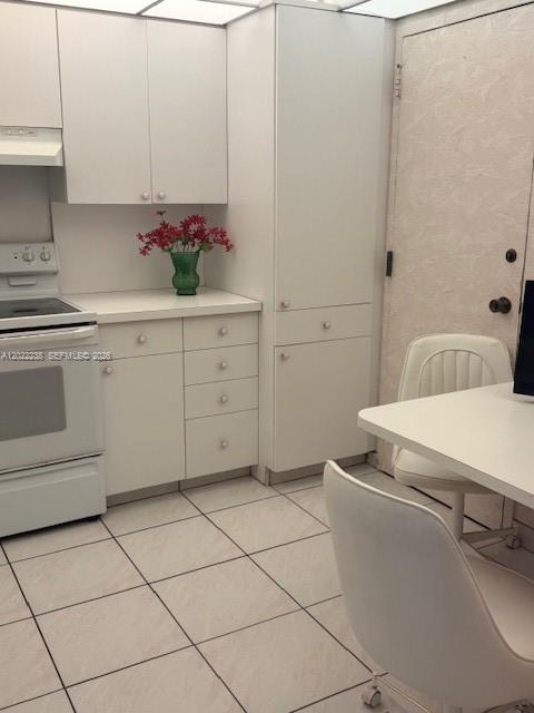 A kitchen features white cabinets, a white stove, a tiled floor, and a small table — 1965 S Ocean Dr # 9K, Hallandale Beach FL 33009, HALLANDALE BEACH, FL