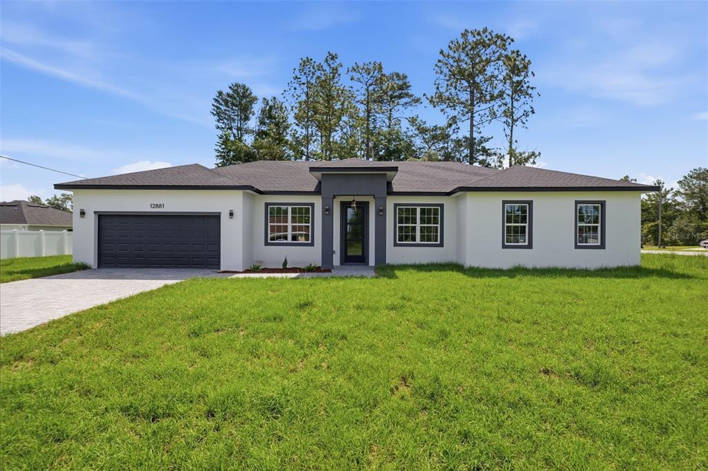 A single-story house with a white stucco exterior, dark trim, and a two-car garage — 12881 SW 56TH TERRACE, OCALA, FL