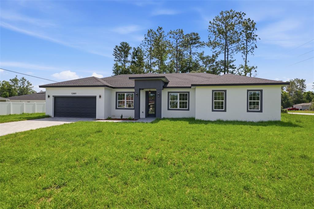 A single-story house with a white stucco exterior, dark gray trim, and a two-car garage — 12881 SW 56TH TERRACE, OCALA, FL