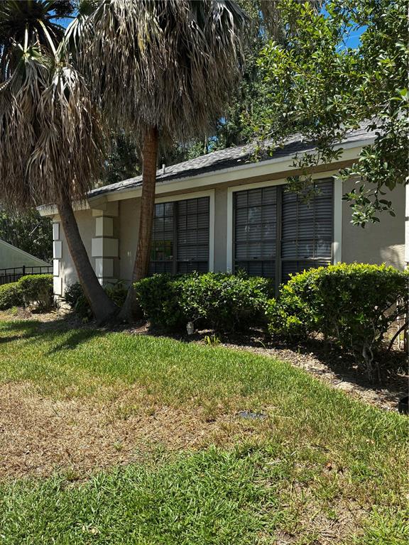 A single-story house exterior features beige siding, dark-framed windows, and tall palm trees — 1701 SE 24TH ROAD UNIT 201, OCALA, FL