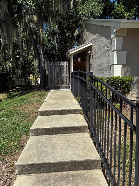 A concrete walkway with steps leads to the entrance of a house with a fence — 1701 SE 24TH ROAD UNIT 201, OCALA, FL