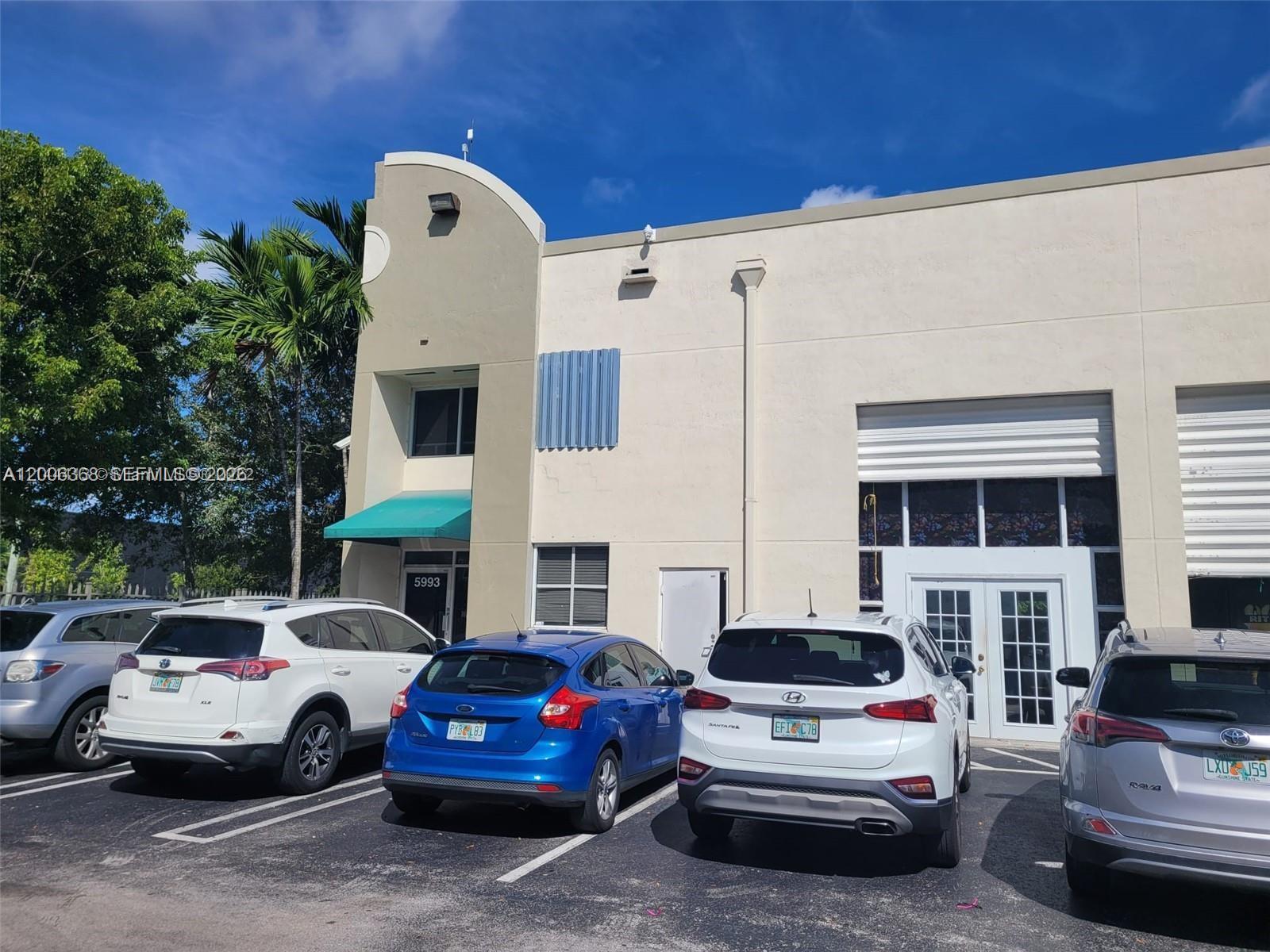 The exterior of a commercial building features a parking lot with several parked cars — 5993 NW 102nd Ave # 7, Doral FL 33178, DORAL, FL