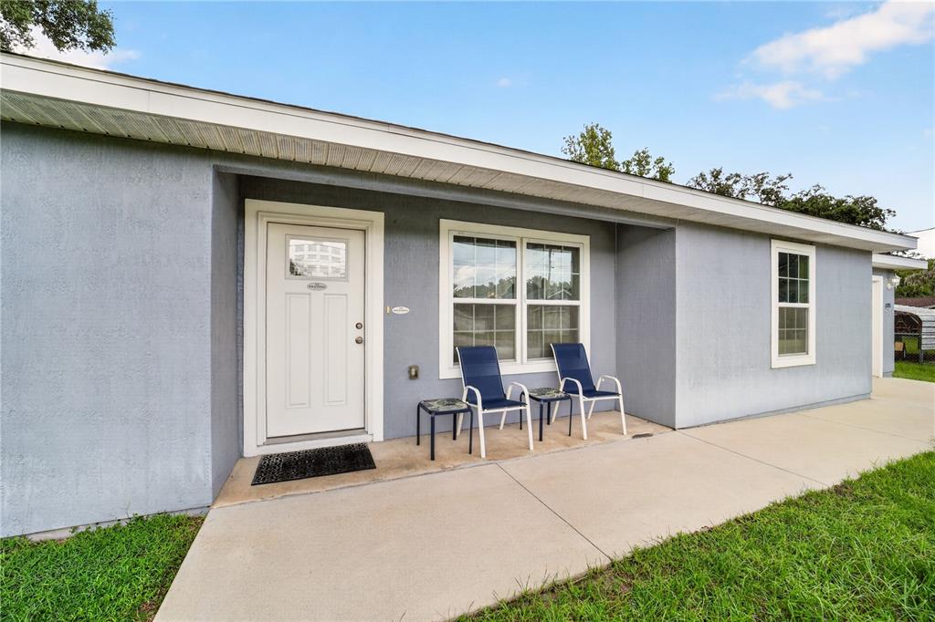 A light blue house exterior features a white front door, a window, and two chairs — 12203 SE 87TH COURT, BELLEVIEW, FL