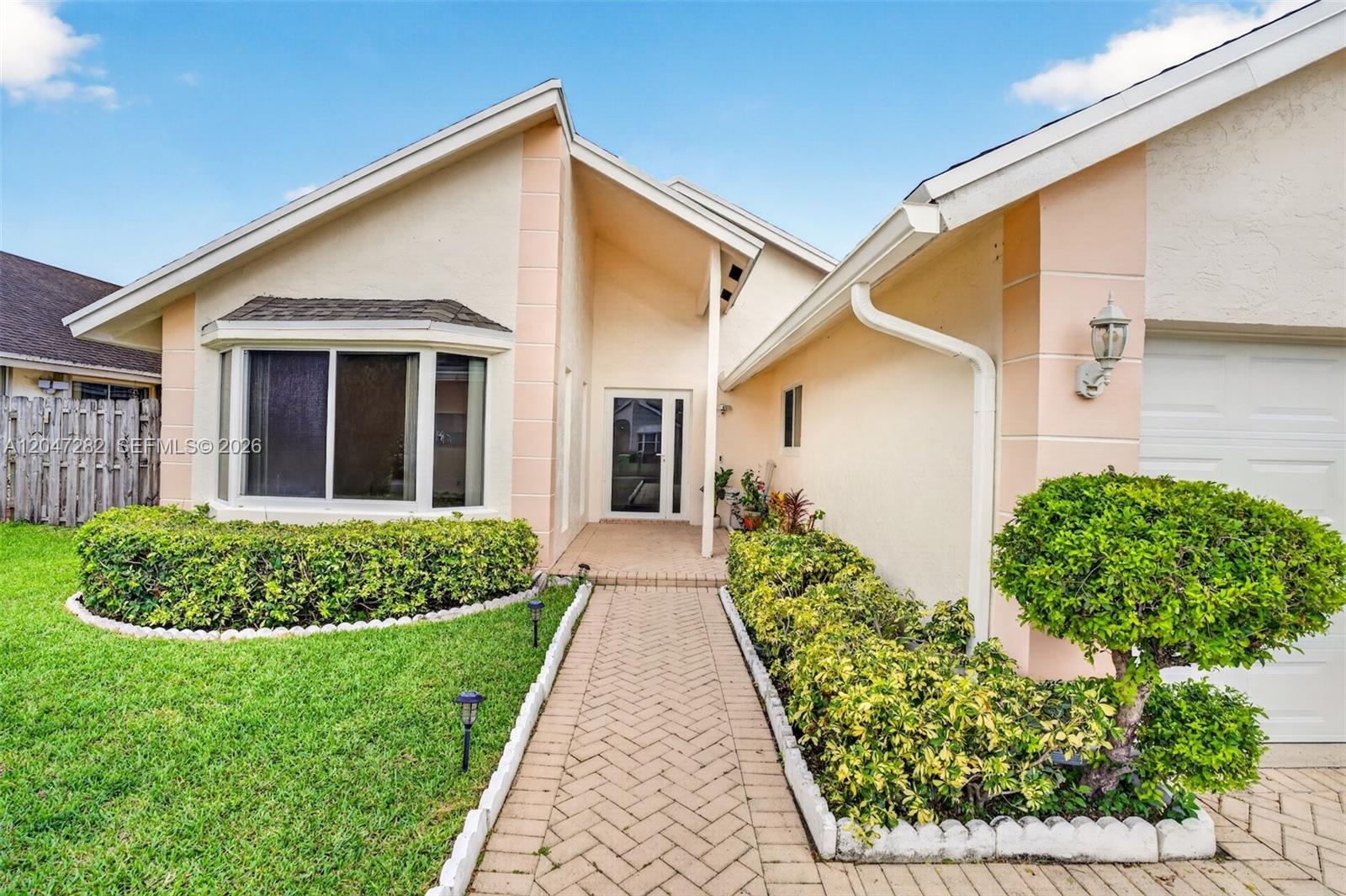 The exterior of a single-story house features a brick walkway, manicured hedges, and a garage — 4495 NW 99th Ave, Sunrise FL 33351, SUNRISE, FL