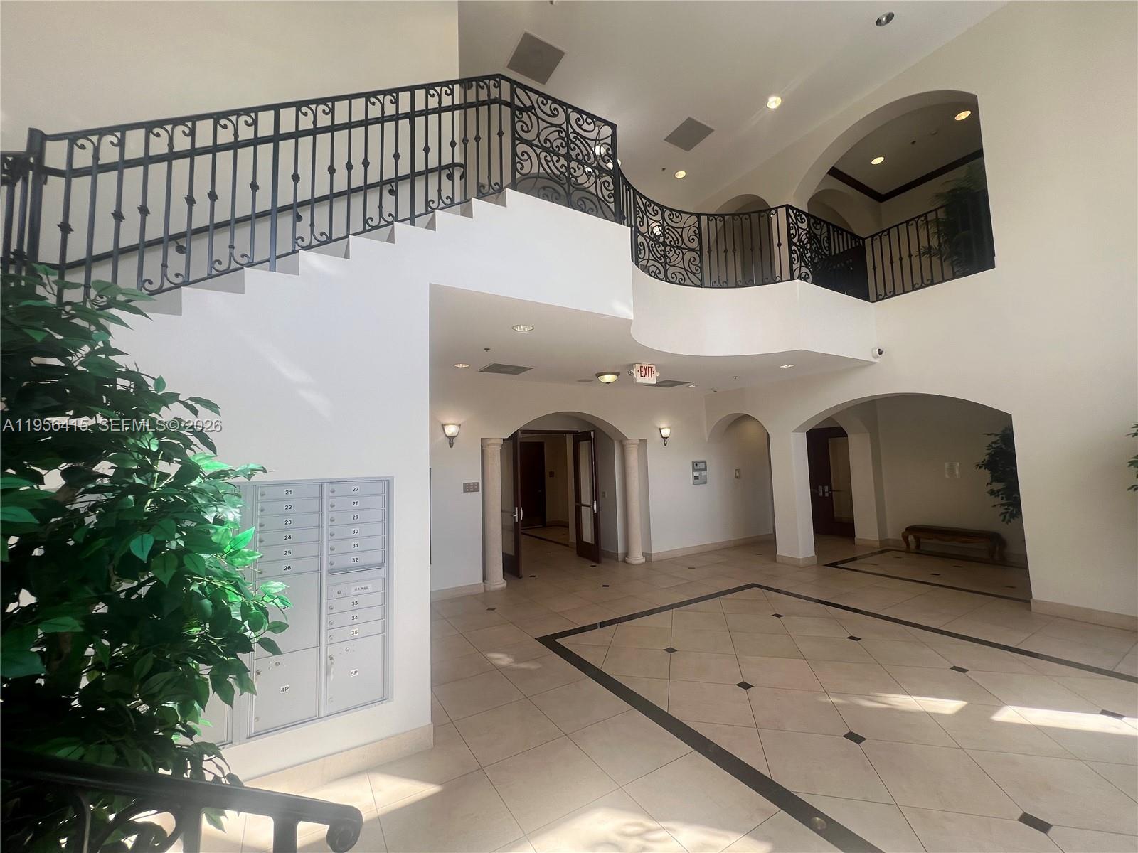 A spacious lobby features a curved staircase with wrought iron railings and tiled flooring — 2893 Executive Park Dr # 125, Weston FL 33331, WESTON, FL