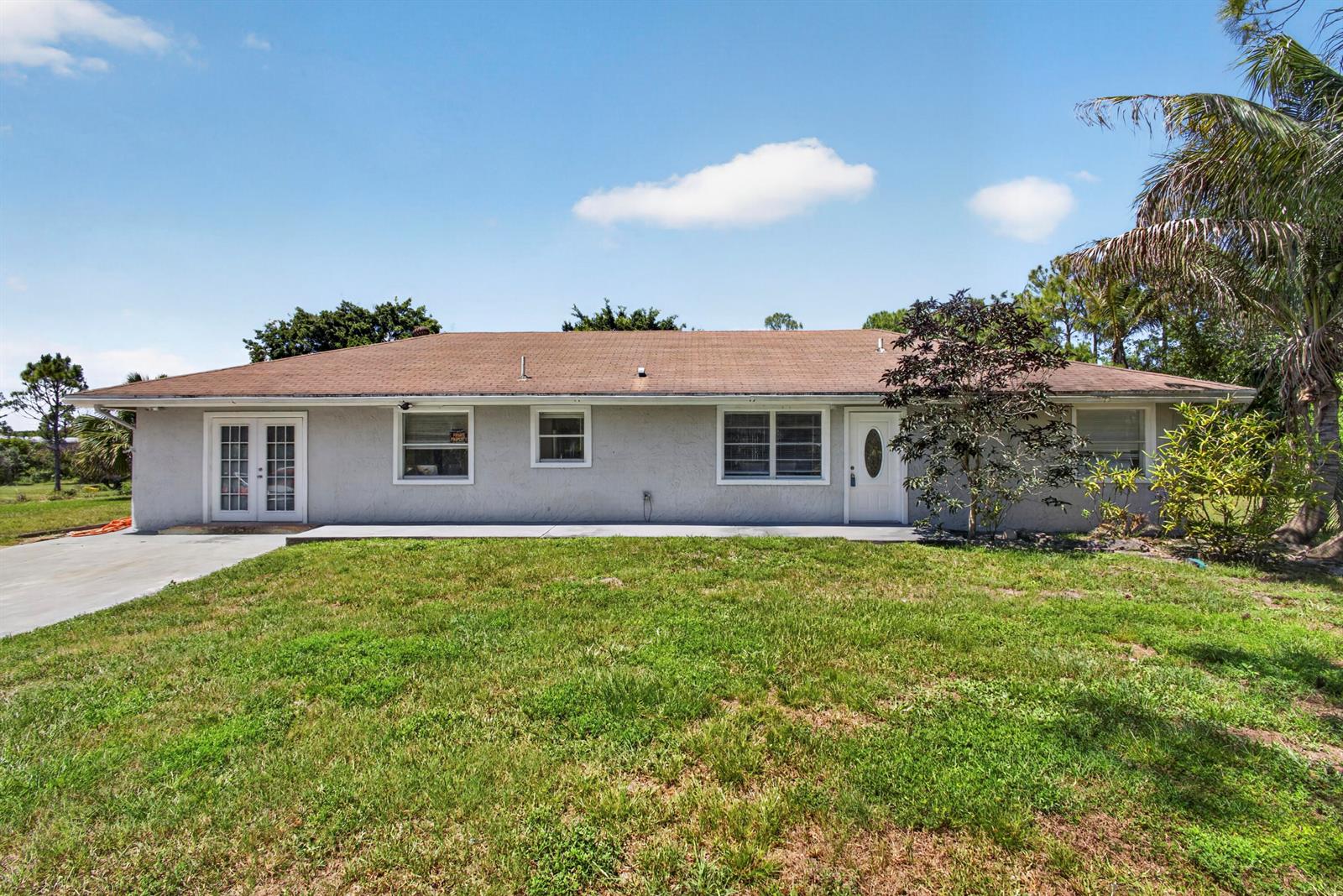 A single-story house with a light gray stucco exterior, a brown roof, and a lawn — 16663 89th Place N, FL 33470, FL