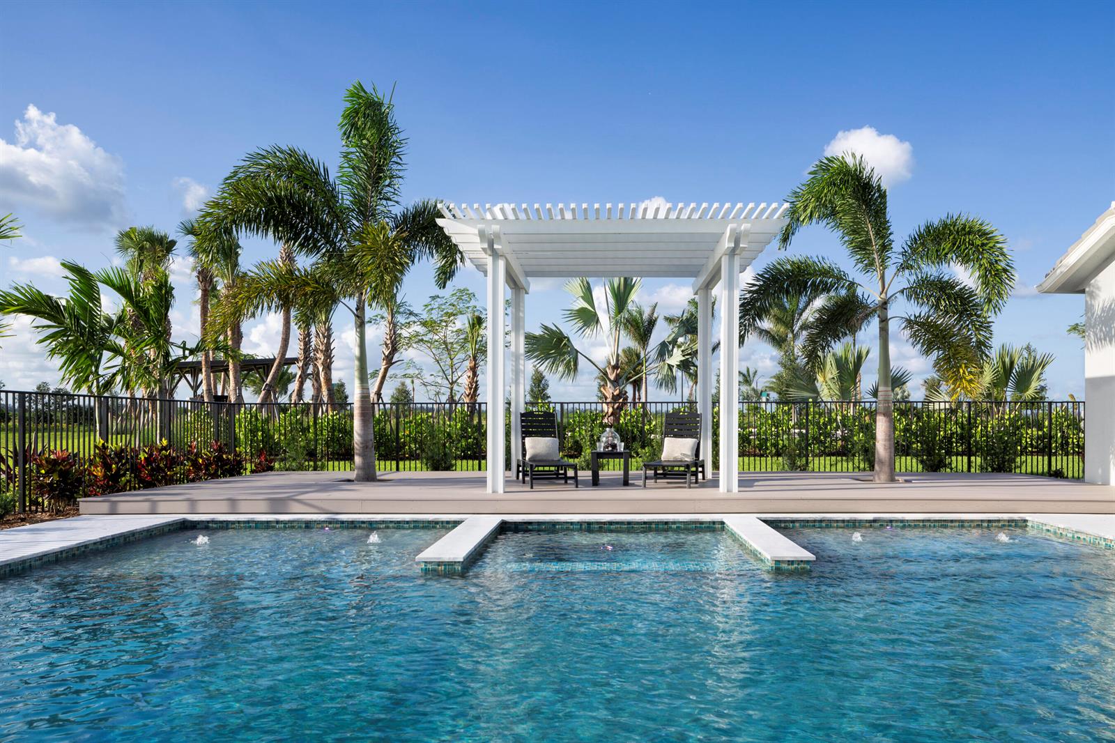 A backyard swimming pool features a white pergola with two chairs on a wooden deck — 4506 Estates Circle, Westlake FL 33470, WESTLAKE, FL