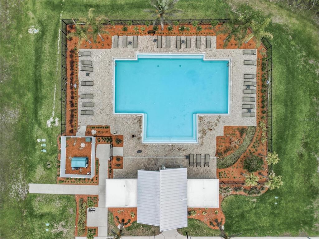 An aerial view shows a rectangular swimming pool with a sun deck, lounge chairs, and landscaping — 1251 SAND TRAP COURT, DAYTONA BEACH, FL